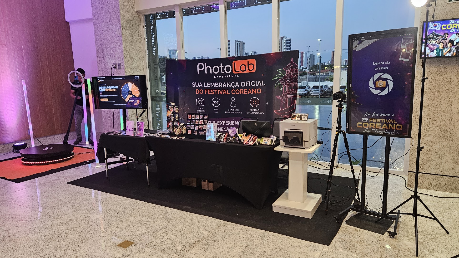 Estande da CajuLba no festival coreano de teresina. Mesa com botton, cards, impressora, Totem interativo, Plataforma 360